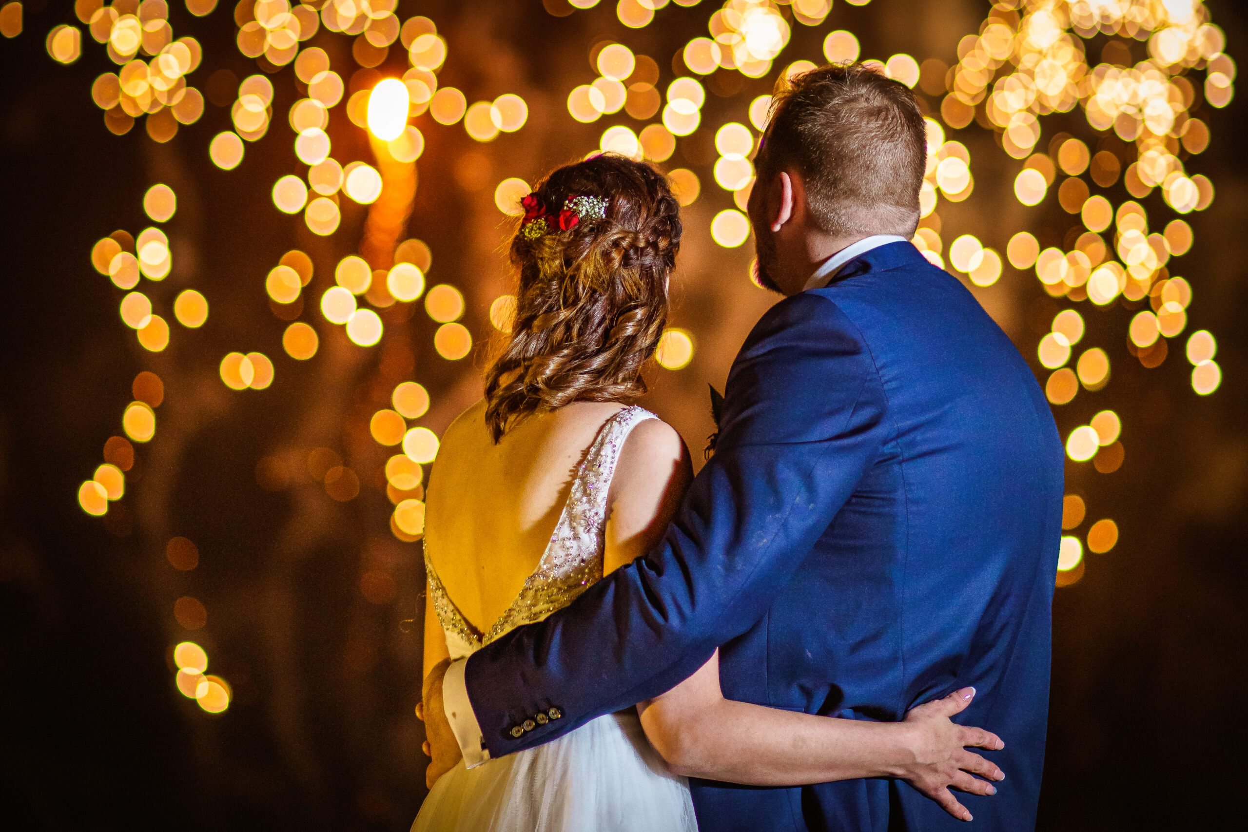 Bridge and groom hug and watch a firework display.