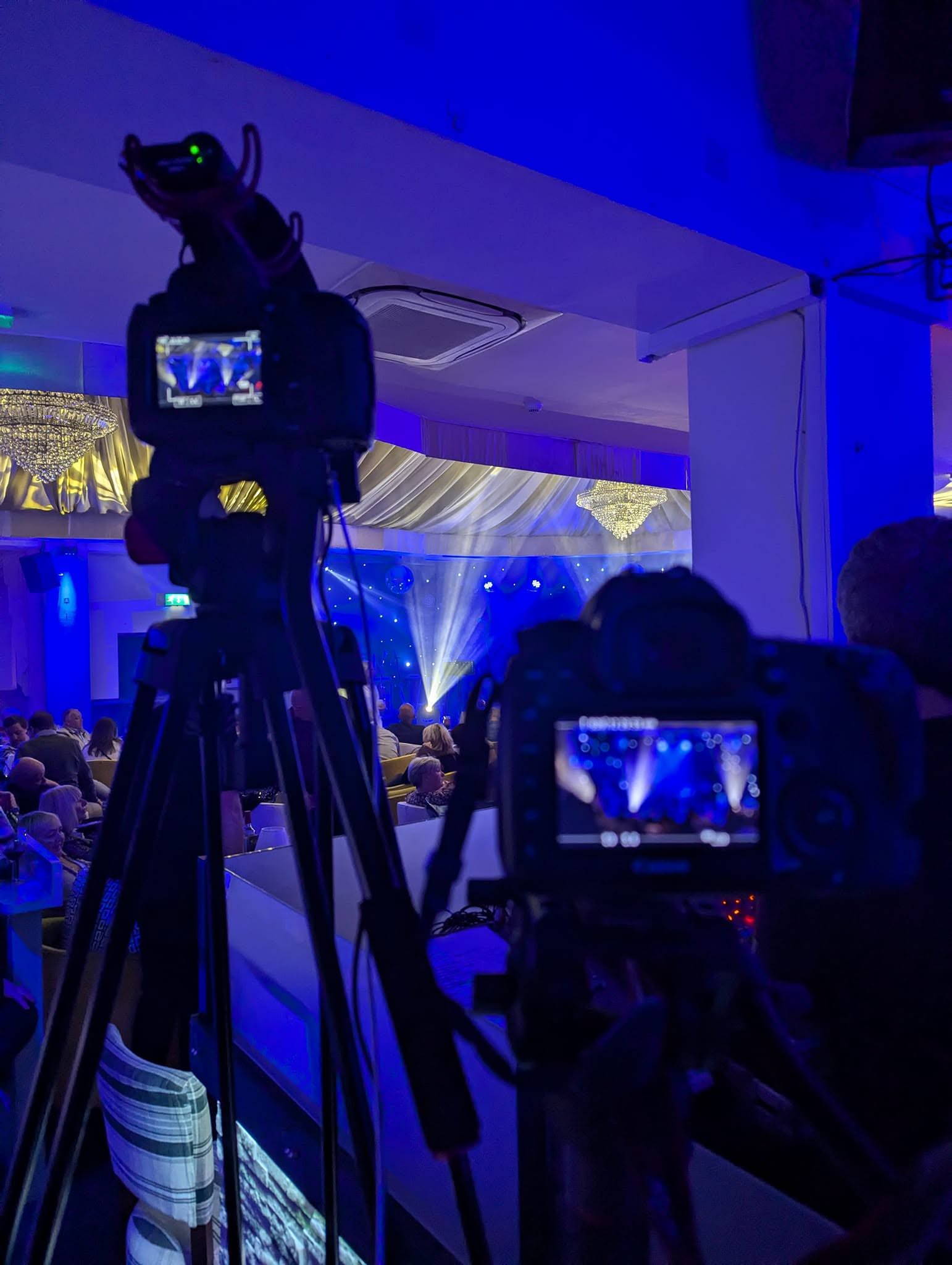 Two cameras set up for filming entertainment at a wedding reception.