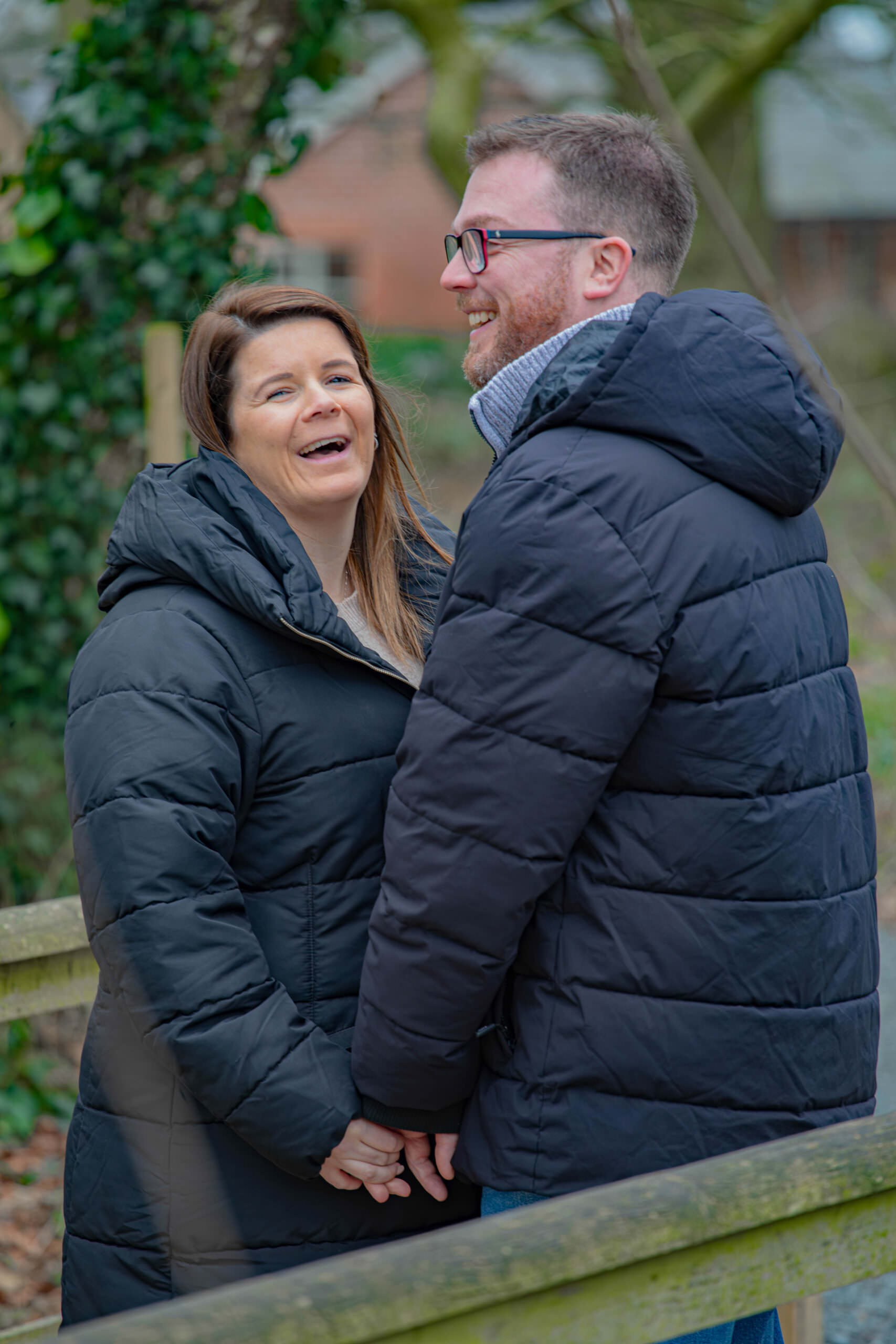 Couple hold hands and laugh during a pre wedding photoshoot.